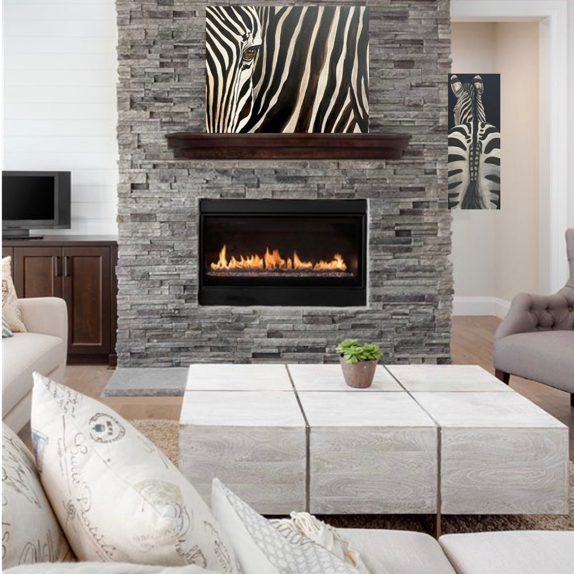 A zebra eye painting displayed above a warm fire on gray stone fireplace. A Zebra Tail painting hangs on back wall behind it to compliment the main piece. Both pieces painted by Terrinye.